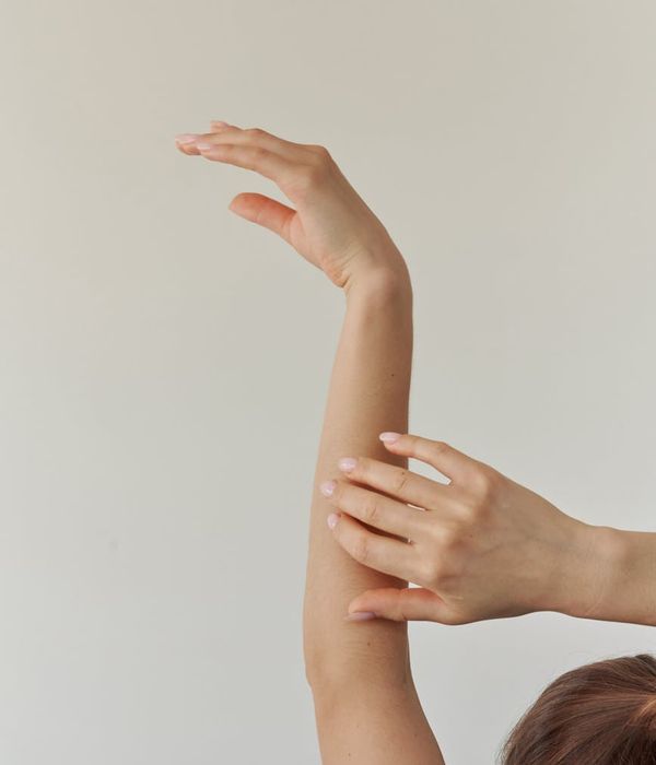 Woman in a calm yoga pose against a soft, neutral background.